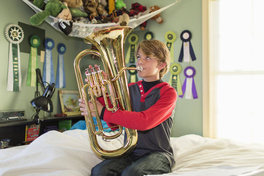 Boy playing tuba in bedroom