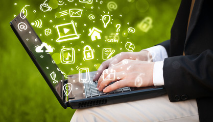 Hand writing on notebook computer with media icons and symbols