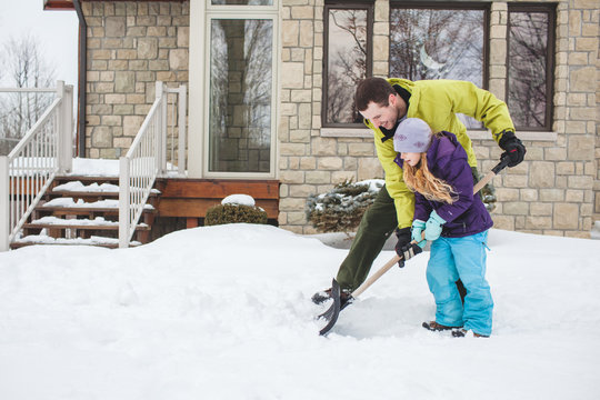 Father helping daughter to shovel snow