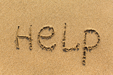 HELP - written manually on the texture of sea sand.