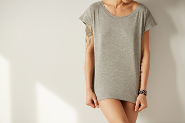 Closeup photo of stylish girl wearing blank t-shirt and looking down. Young girl wearing grey blank...