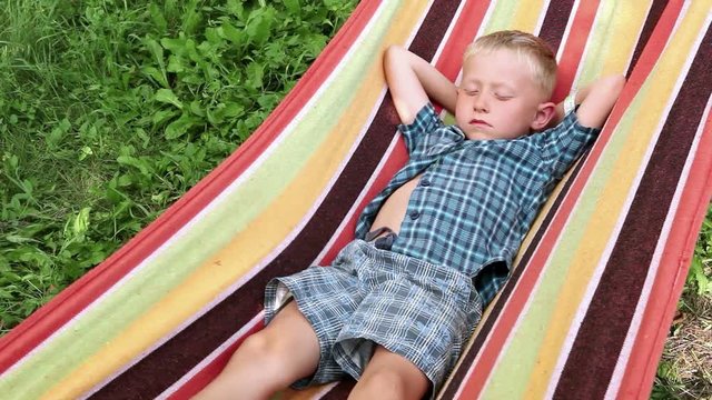 A wee blond lad chilling out in the hammock on summer afternoon