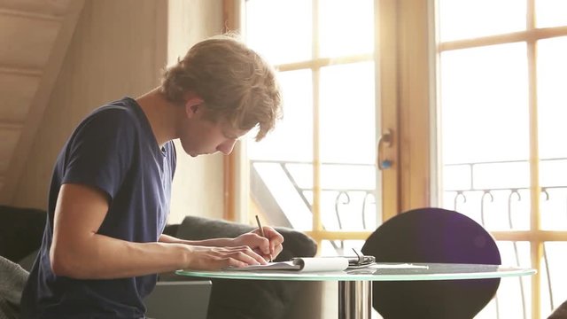 A left-handed student doing his homework, musing about the answers