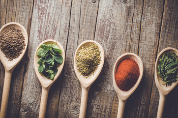 Aromatic herbs and spices on wooden spoons