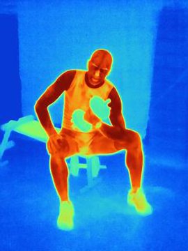Thermal image of young male athlete training with weights. The image shows the heat produced by the muscles