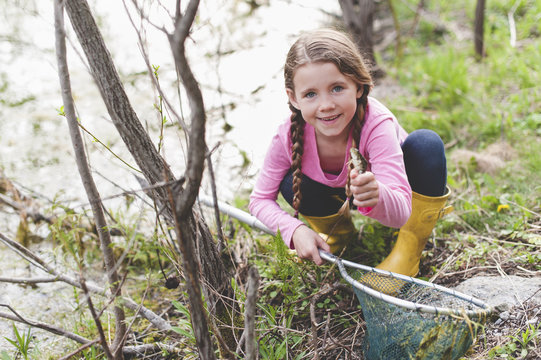 Portrait of girl holding up frog and fishing net