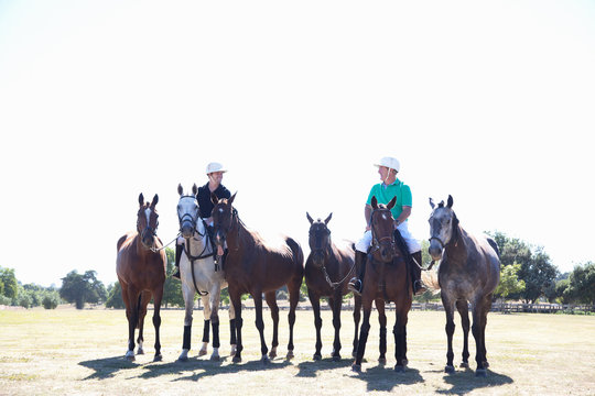 Polo players, leading horses in from field