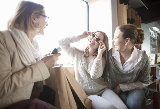 Three generation females trying on sunglasses in shop