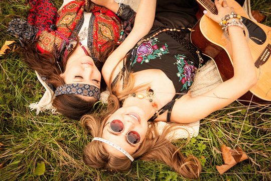 Hippy girls lying in field with guitar