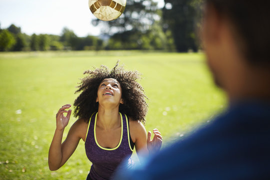Young woman heading football in park