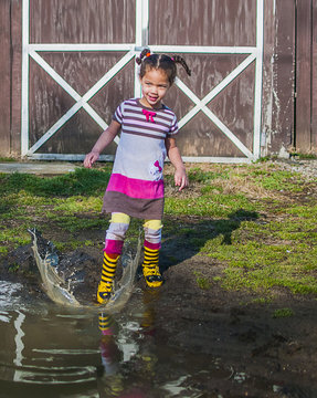 Girl stamping and splashing in garden puddle