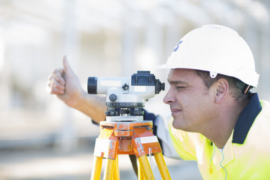 Surveyor looking through level on construction site