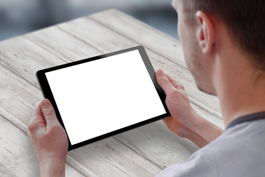 Tablet with isolated screen for mockup in man hands. Man sitting and holding tablet on table. Isolated device screen for design, interface promotion.