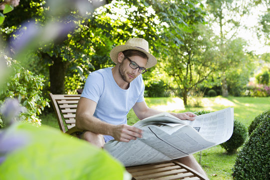 Mid adult man reading newspaper in garden