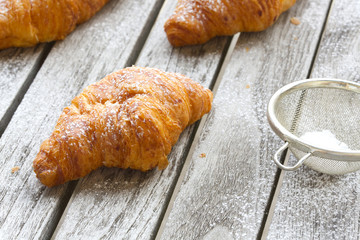 French croissant on a gray wooden surface. Closeup