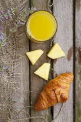 A glass of fresh pineapple juice and a French crescent roll. Background