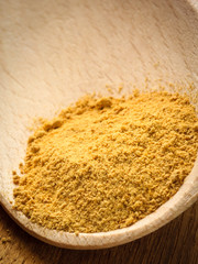 Pile of ground ginger on wooden spoon
