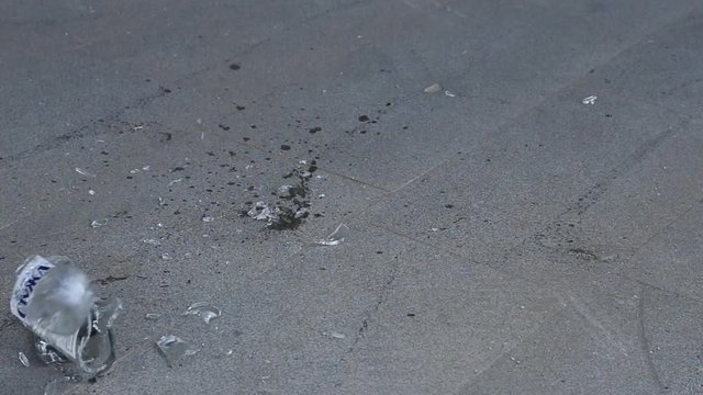 Reverse,slow motion smashing a bottle on asphalt
