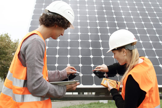 Man and woman working on photo voltaic panels