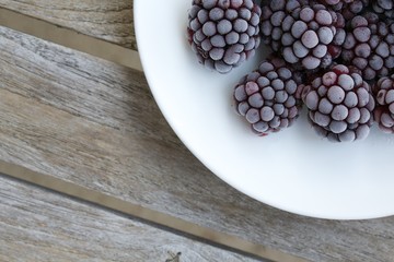 Frozen blackberries on a white plate. Closeup