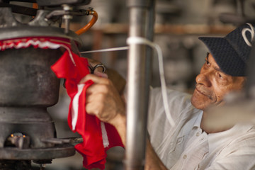 Hat maker cutting and stretching fabric in workshop