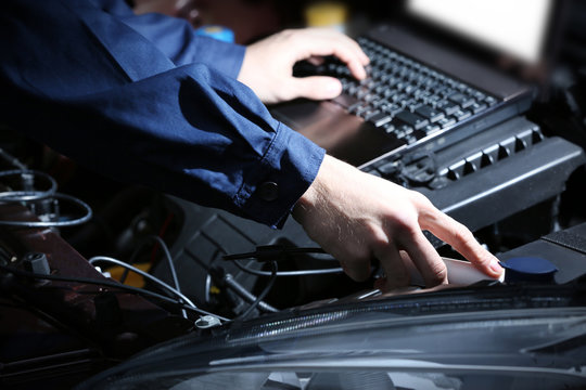 Professional auto mechanic working in repairing service, close-up. Car diagnostics concept