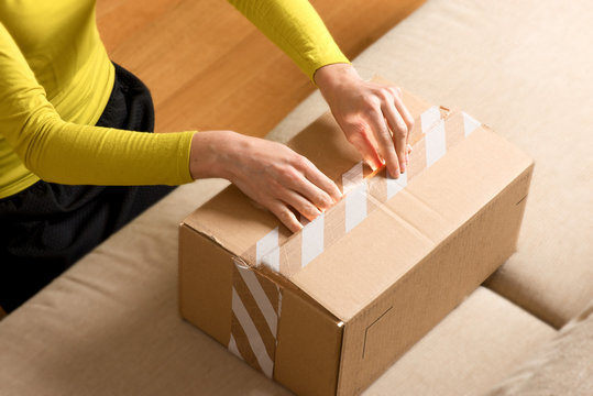 woman opening cardboard box at home, online shopping