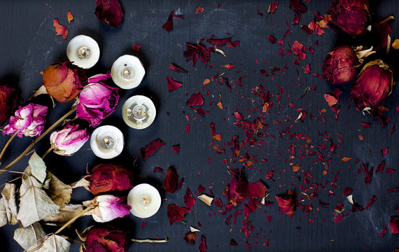 Dried Roses And Burning Candles On A Black Chalk Boar. Backgroun