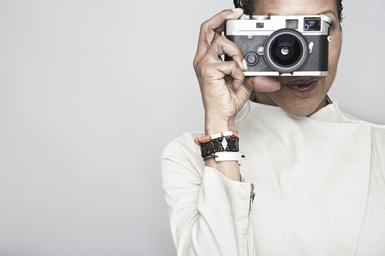 Studio portrait of mature woman holding up camera