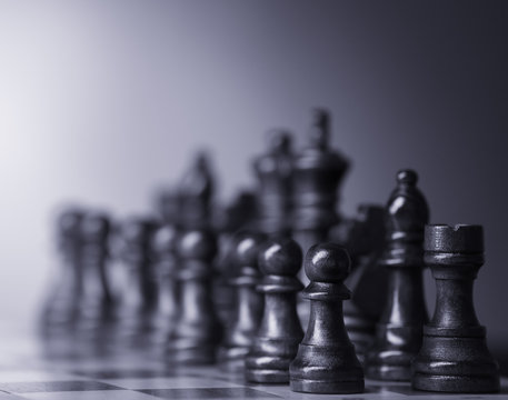 Chess pieces and game board on light blurred background