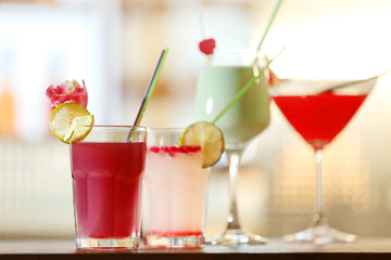 Glasses of cocktails on bar background