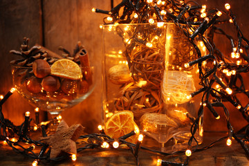 Electric garland with pine cones and hazelnuts on wooden background