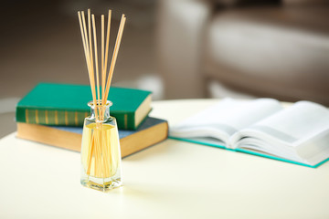 Handmade reed freshener with books on white table in living room, close up