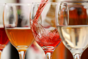 Red wine pouring into glasses, closeup