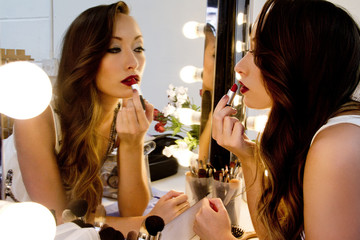 Woman applying lipstick in mirror