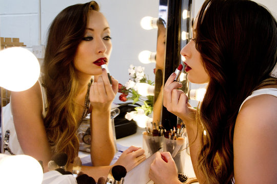 Woman applying lipstick in mirror