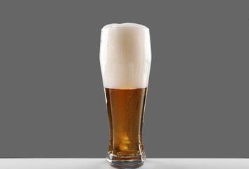 Glass of lager beer on grey background