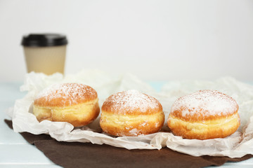 Delicious donuts with powdered sugar on parchment closeup