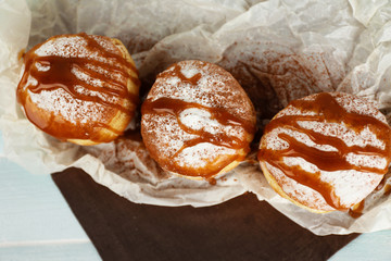 Delicious donuts with caramel on parchment, top view
