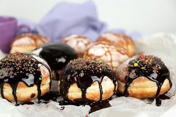 Delicious donuts poured with chocolate and caramel on parchment closeup