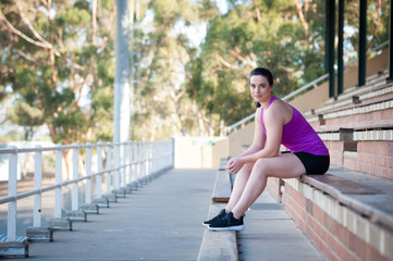 Fototapeta premium Young feamle model sat in an empty stadium