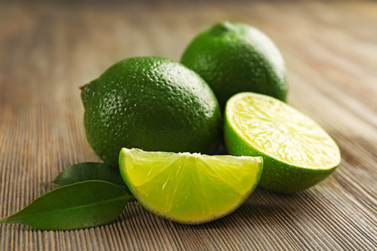 Limes and slices on wooden table, closeup