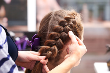Fototapeta premium Professional hairdresser braiding clients hair