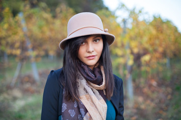Spring and autumn portrait of cute young woman, posing with a hat, looking at the camera