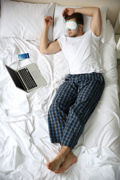 Young man sleeping with blindfold in bed at home