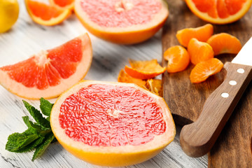 Pieces of different citrus fruit on wooden cutting board