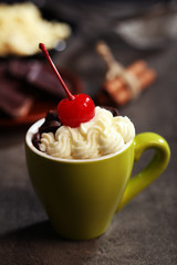 Chocolate cake in a green mug  with whipped cream and a cherry on top, close up