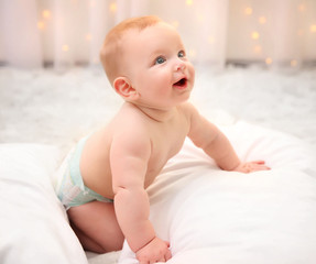 Adorable baby in diaper with pillows on the floor, close up