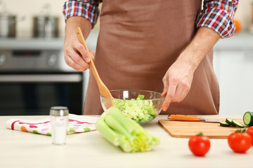 Man cooking vegetable salad in kitchen