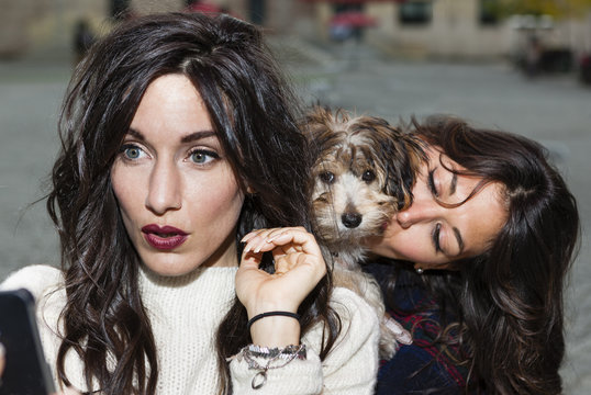 Friends holding pet dog for photograph